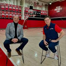 Two men sitting in a basketball court.