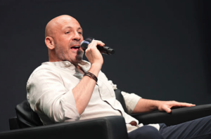 Man speaking into microphone on stage.