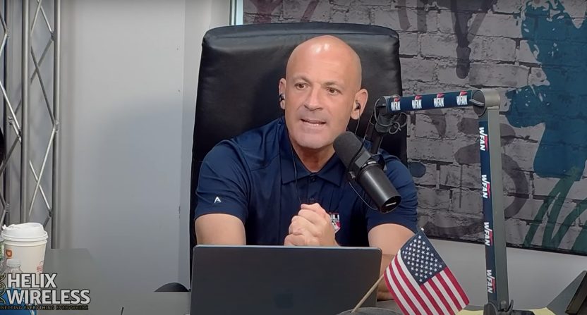 Man speaking into microphone at a desk.